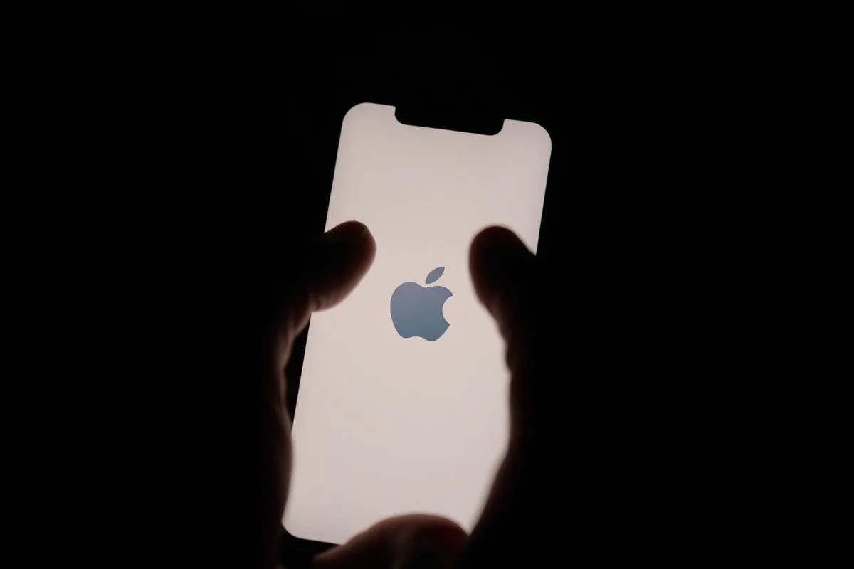 Hand holding iPhone showing Apple boot logo — factory reset before selling