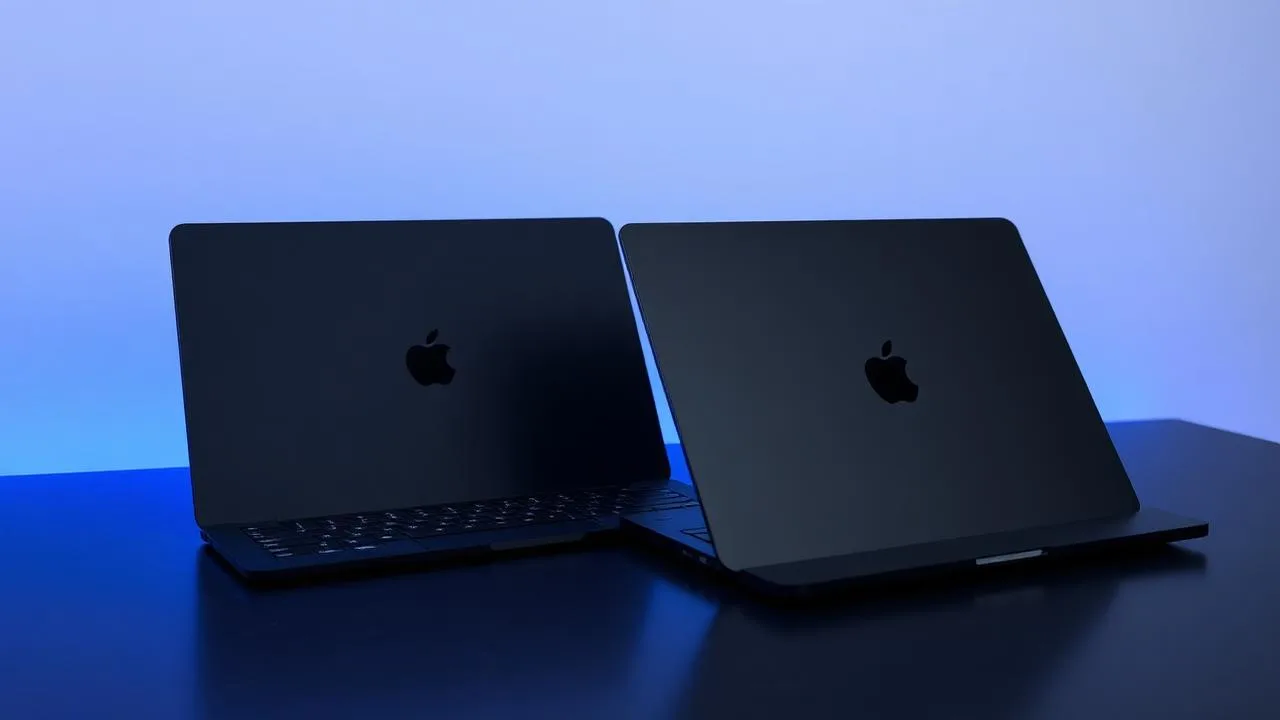 Closed Space Black MacBook Pro 14-inch and 16-inch on a dark slate desk under cool blue rim light